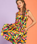 Woman twirling in colorful tropical leaf print sleeveless mini dress