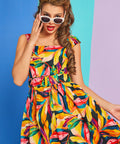 Woman wearing colorful tropical print dress with white cat-eye sunglasses