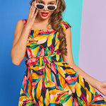 Woman wearing colorful tropical print dress with white cat-eye sunglasses