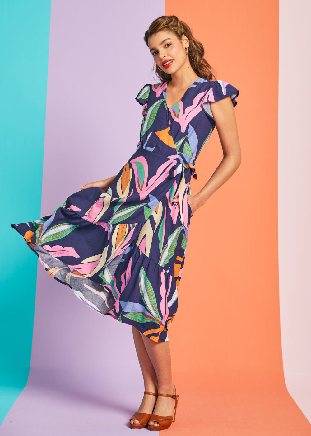 Woman twirling in colorful abstract botanical midi dress with tiered hem