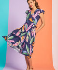 Woman twirling in colorful abstract botanical midi dress with tiered hem