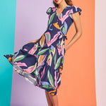 Woman twirling in colorful abstract botanical midi dress with tiered hem