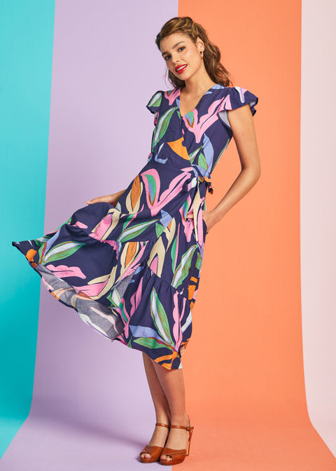 Woman twirling in colorful abstract botanical midi dress with tiered hem