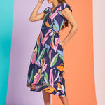Side view of tropical print wrap-style midi dress with flutter sleeves and pockets