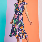 Woman wearing colorful tropical wrap dress with side tie waist and pockets