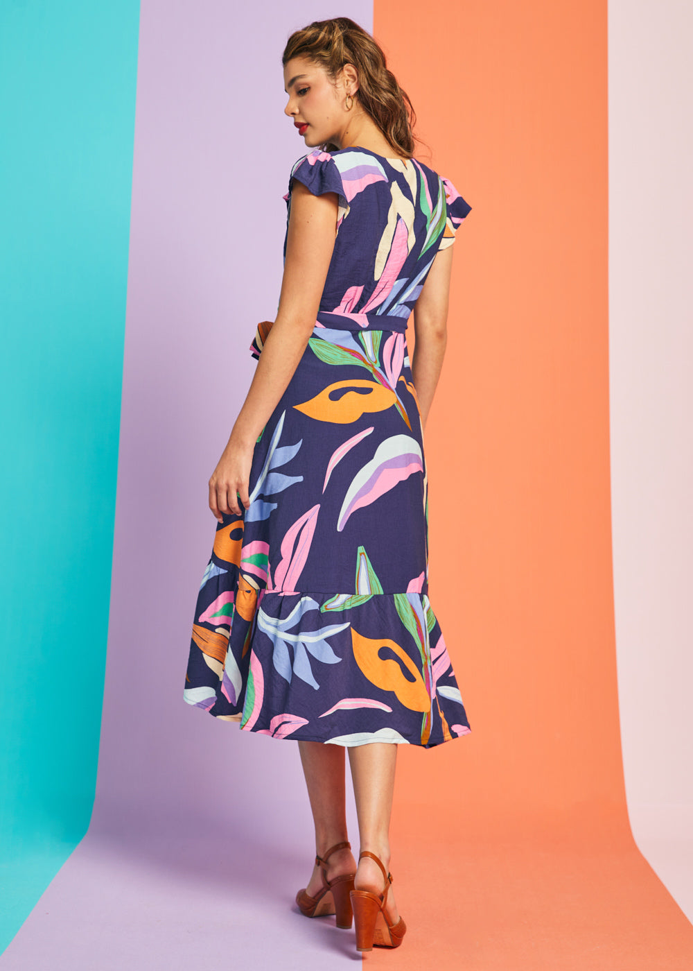 Back view of abstract botanical midi dress with flutter sleeves and asymmetrical hem