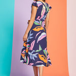 Back view of abstract botanical midi dress with flutter sleeves and asymmetrical hem