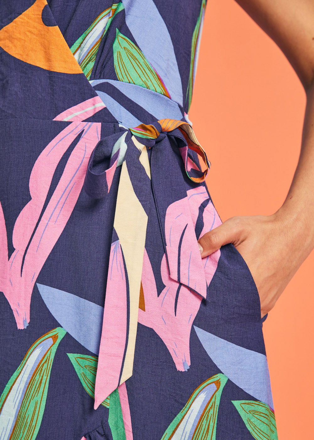 Close-up of adjustable side tie waist detail on tropical print midi dress