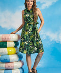 Woman wearing tropical palm print sleeveless shirt dress with waist tie and pockets