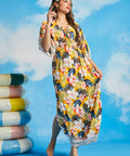 Woman walking in tropical floral resort maxi dress with border print hem