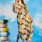 Woman walking in tropical floral resort maxi dress with border print hem