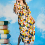 Woman walking in tropical floral resort maxi dress with border print hem