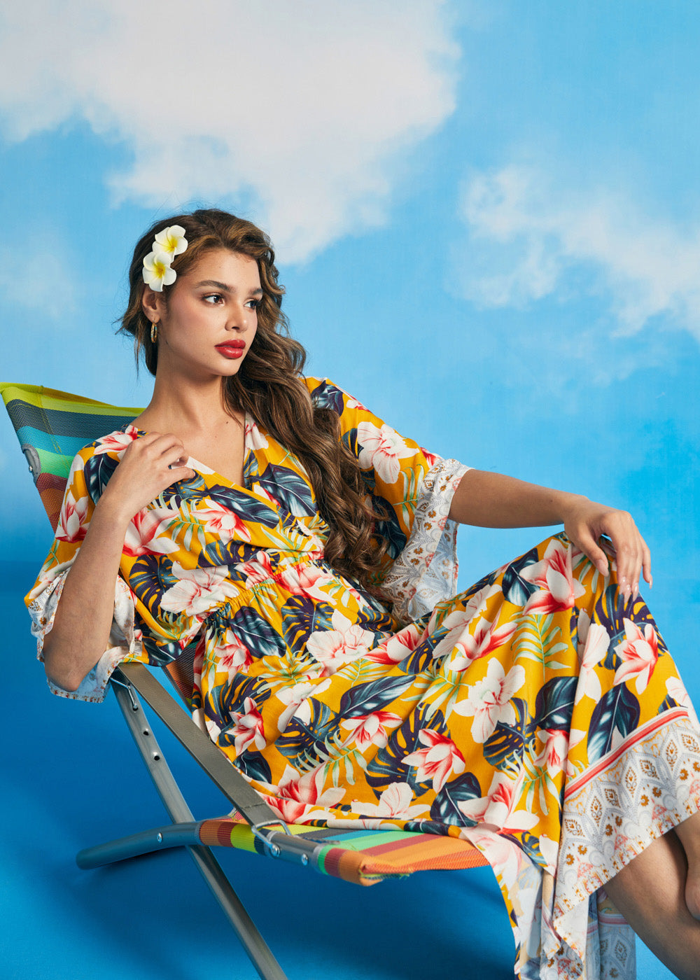 Woman lounging in tropical floral maxi dress with side slit hem