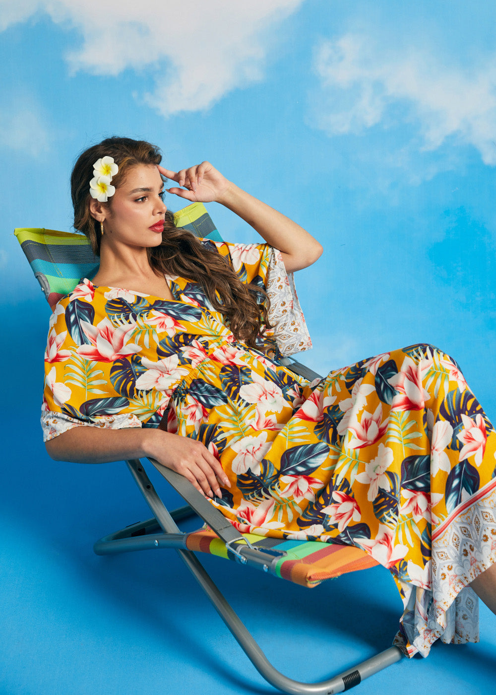 Woman reclining in tropical floral faux-wrap maxi dress with relaxed silhouette