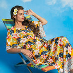 Woman reclining in tropical floral faux-wrap maxi dress with relaxed silhouette