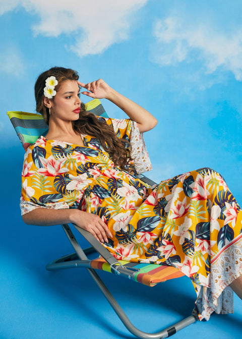Woman reclining in tropical floral faux-wrap maxi dress with relaxed silhouette