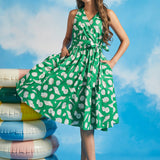 Model wearing green seashell print faux-wrap vacation dress with waist tie and flowy skirt