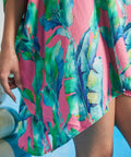 Close-up of tropical watercolor leaf print on pink textured fabric