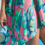 Close-up of tropical watercolor leaf print on pink textured fabric