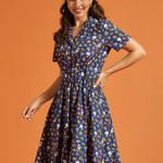 Woman wearing a blue dress with button front and multi color novelty print