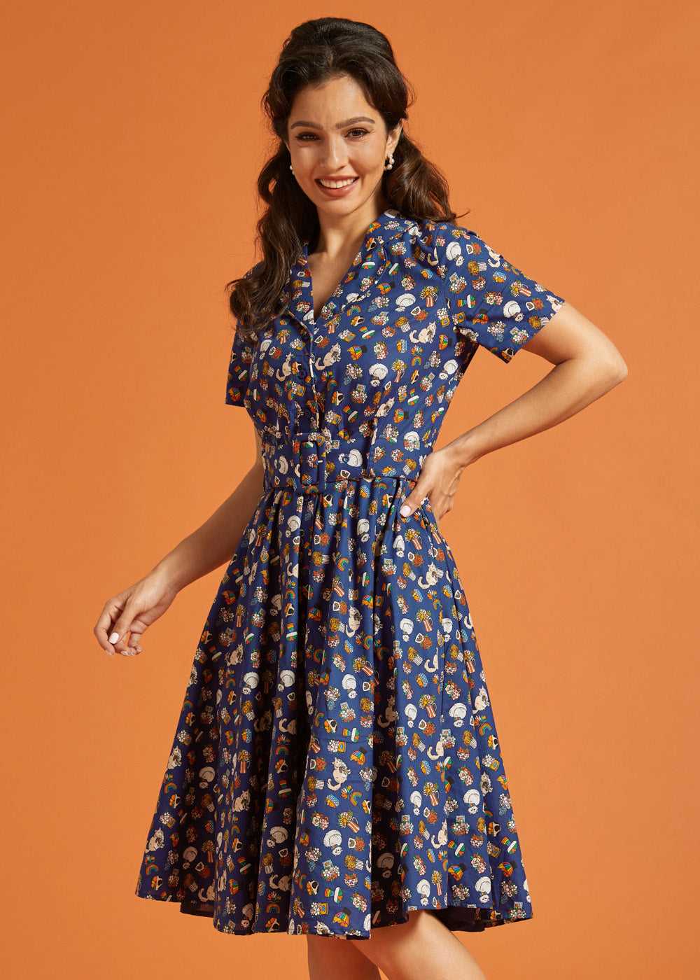 Woman wearing a blue dress with button front and multi color novelty print