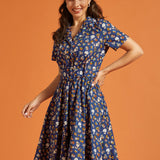 Woman wearing a blue dress with button front and multi color novelty print