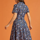 Back view of a woman wearing a blue vintage inspired fit and flare printed dress
