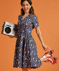 Woman in a navy blue rainbow print dress holding a retro radio and red roller skates