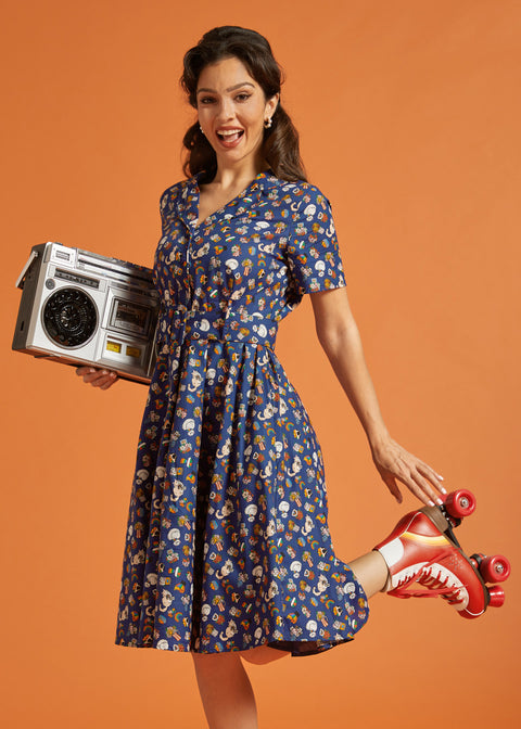 Woman in a navy blue rainbow print dress holding a retro radio and red roller skates