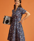 Woman in a cotton summer dress holding a boombox against an orange background