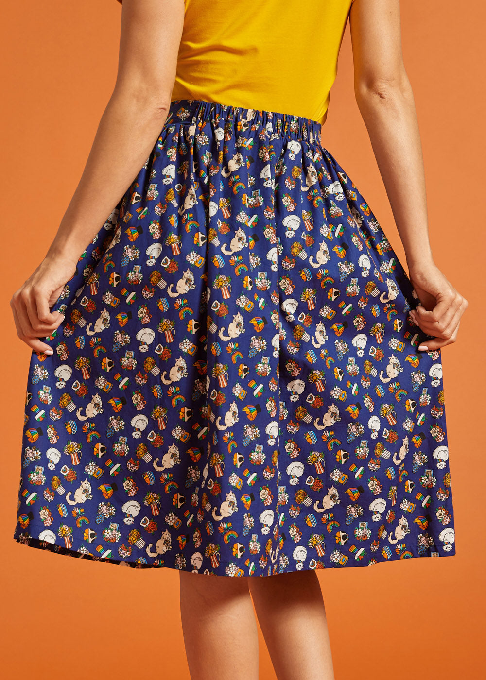 Back view of a woman wearing a blue novelty patterned skirt with an elastic back waist