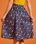 Back view of a woman wearing a blue novelty patterned skirt with an elastic back waist