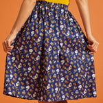 Back view of a woman wearing a blue novelty patterned skirt with an elastic back waist