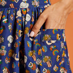 Close up of pocket on colorful patterned fabric skirt with cats and rainbows on a blue background