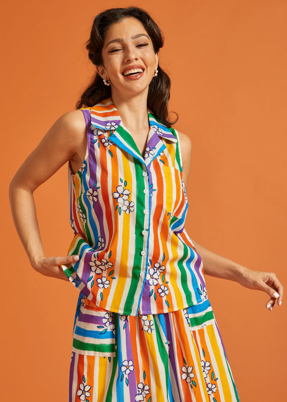 Woman wearing a colorful striped sleeveless cotton summer blouse and matching skirt set
