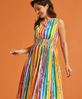 Woman wearing a rainbow stripe pride dress against an orange background