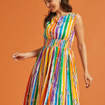 Woman wearing a rainbow stripe pride dress against an orange background