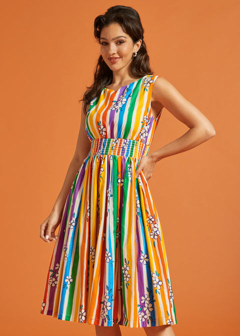 Woman wearing a colorful striped dress against an orange background