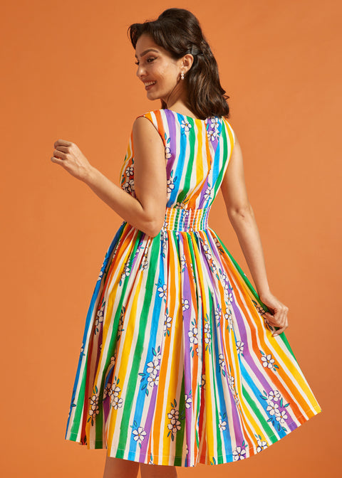 Woman wearing a colorful striped summer dress against an orange background