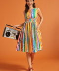 Woman in a sleeveless rainbow striped dress holding a retro boombox against an orange background