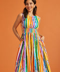 Woman wearing a colorful rainbow striped summer dress against an orange background