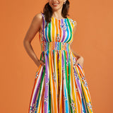 Woman wearing a colorful rainbow striped summer dress against an orange background