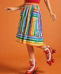 Woman wearing a colorful striped skirt and red roller skates on an orange background