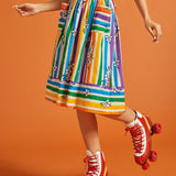 Woman wearing a colorful striped skirt and red roller skates on an orange background