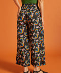 Back view of a woman wearing black wide-leg pants with colorful rainbow and floral pattern