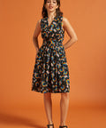 Woman wearing a sleeveless dress with a colorful rainbow floral pattern on an orange background