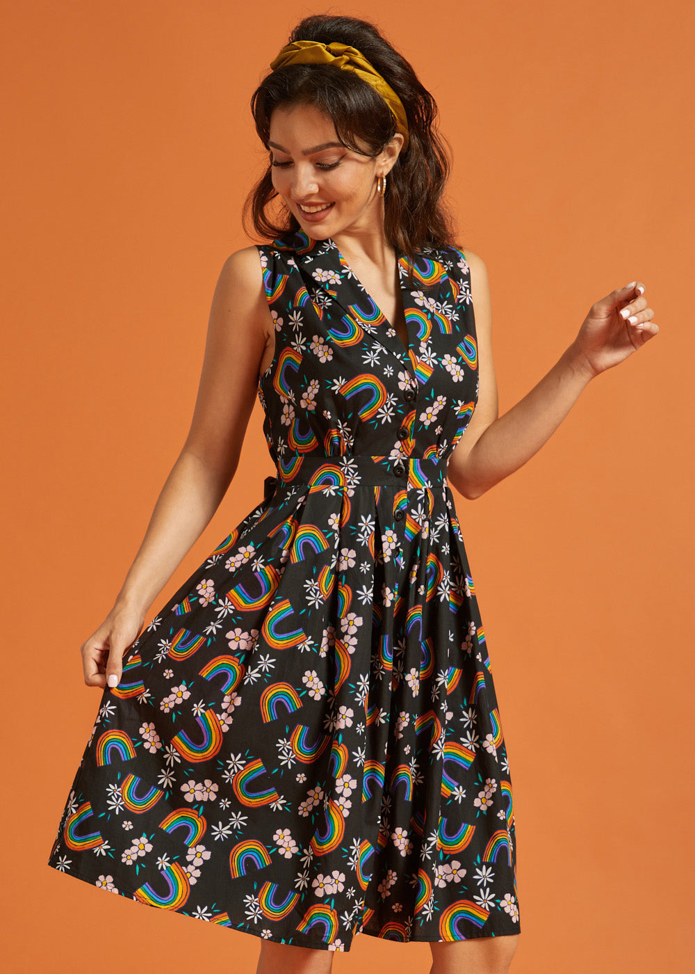 Woman wearing a vintage inspired black dress with rainbow and floral pattern