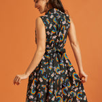 Back view of a woman wearing a dress with rainbow and floral pattern on an orange background