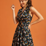 Side view of a woman wearing a black dress with colorful rainbow and floral pattern on an orange background