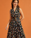 Woman wearing a sleeveless cotton summer dress with rainbow and floral pattern on an orange background